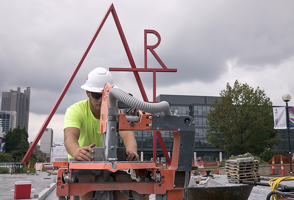 construction worker under the art sign