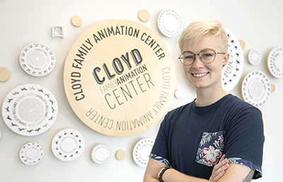 Erica Eppert (Illustration, 2018) in front of the Cloyd Family Animation Center donor wall she designed.