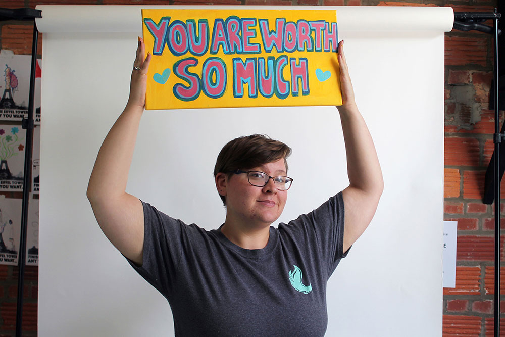 Student holding sign that reads You are worth so much