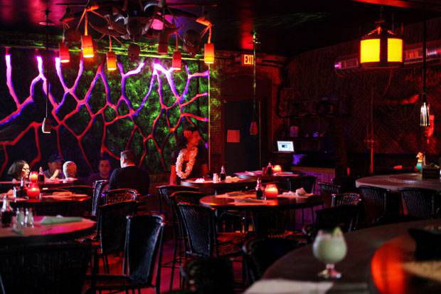 Fine Arts, Interior shot of the Grass Skirt Tiki Room overlooking tables and backlit volcano feature wall 