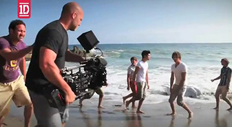 Advertising & Graphic Design, Image of John behind the scenes holding camera shooting One Direction video on the beach 