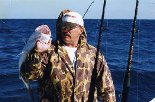 Illustration, Image of man on a boat holding up a fish in a camouflage jacket and hat against a background of blue sky and water 