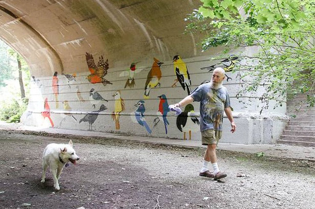 Fine Arts, Man walks his dog next to tunnel mural of painted birds