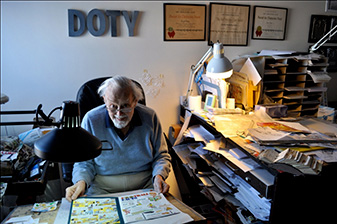 Fine Arts, Photo of Roy poring over a comic book at a cluttered desk