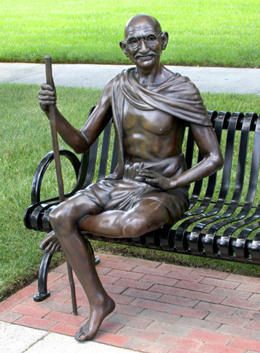 Advertising & Graphic Design, Bronze sculpture of Ghandi with staff sitting on bronze bench against background of green grass and sidewalks