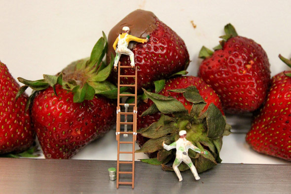 Photo of artwork, small sculptures of people working in coating strawberries with chocolate. Miniature