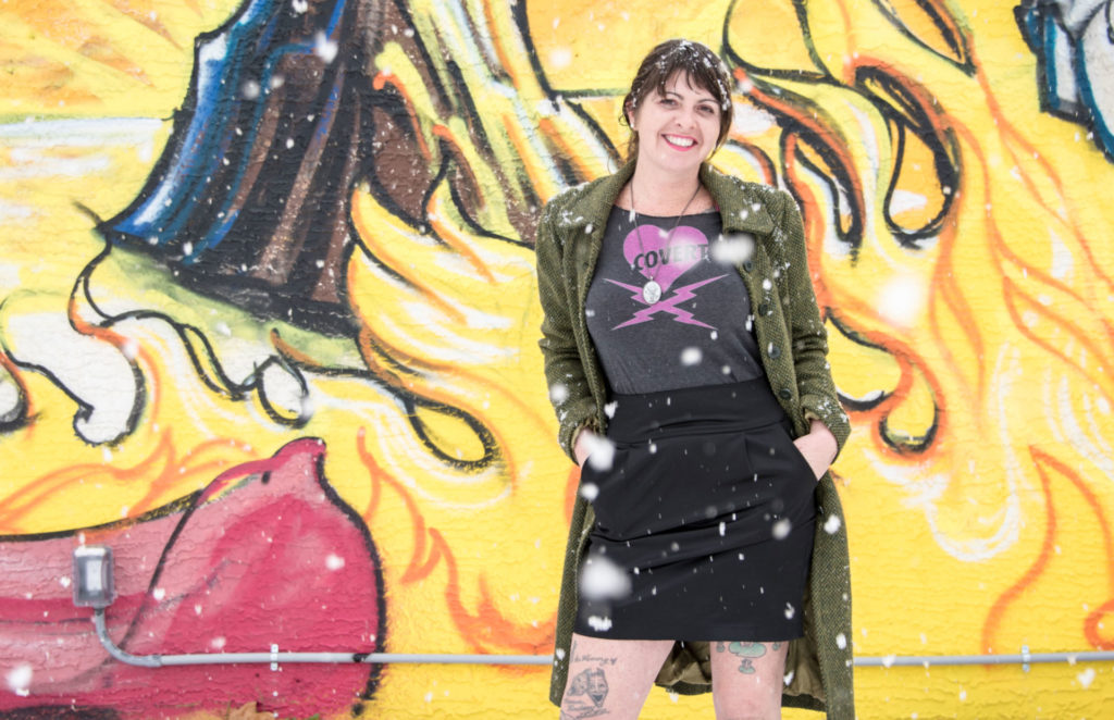 Fine Arts, Image of AJ Vanderelli standing in front of yellow, black, and red mural in the snow