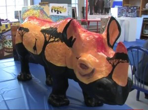 Life at CCAD, photo of faux rhino painted with savannah scenery at sunset in rich golds and reds