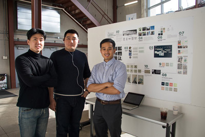 Interior Design, Three students pose for photo in front of table with laptop against a wall with a poster detailing their project