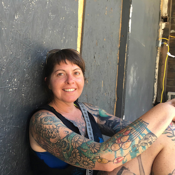 Life at CCAD, Photo of Alicia Jean Vanderelli sitting on the ground against a fence smiling at the camera in Franklinton