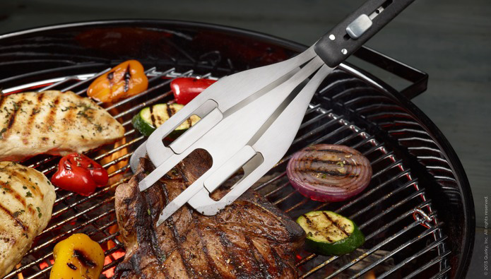 Industrial Design, Image of tong spatula pressing into steak on a grill surrounded by chicken breasts, onions, and bell peppers