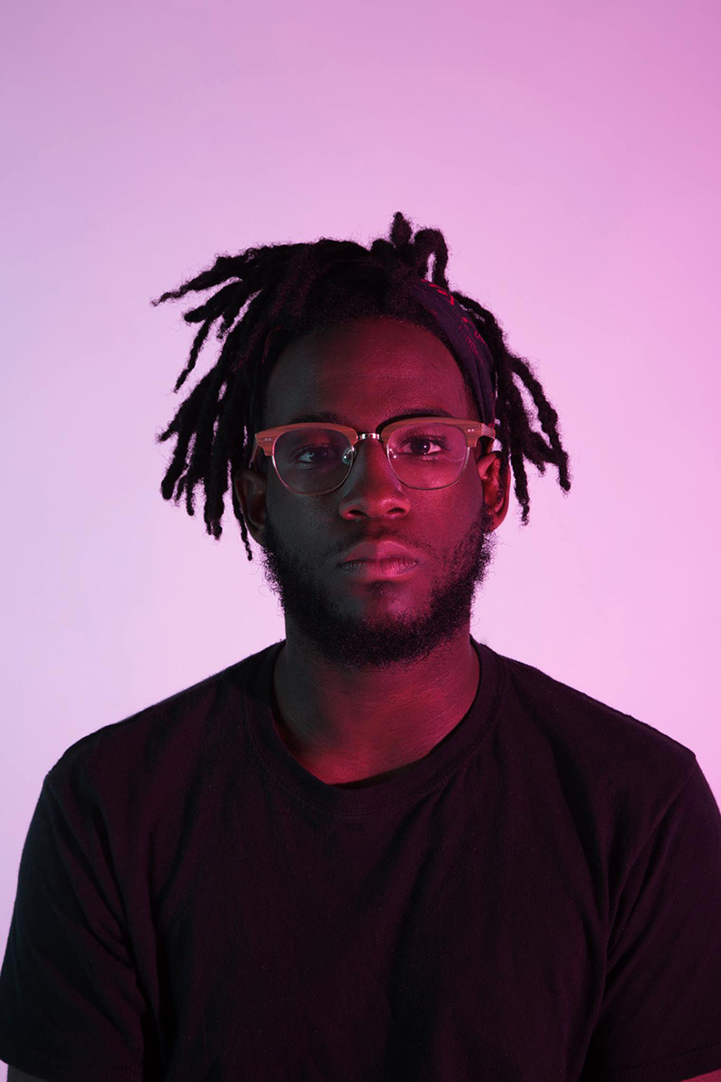 Illustration, Headshot of Marcus in black sweater against a white background, not smiling, with pink lighting shining on face and wall