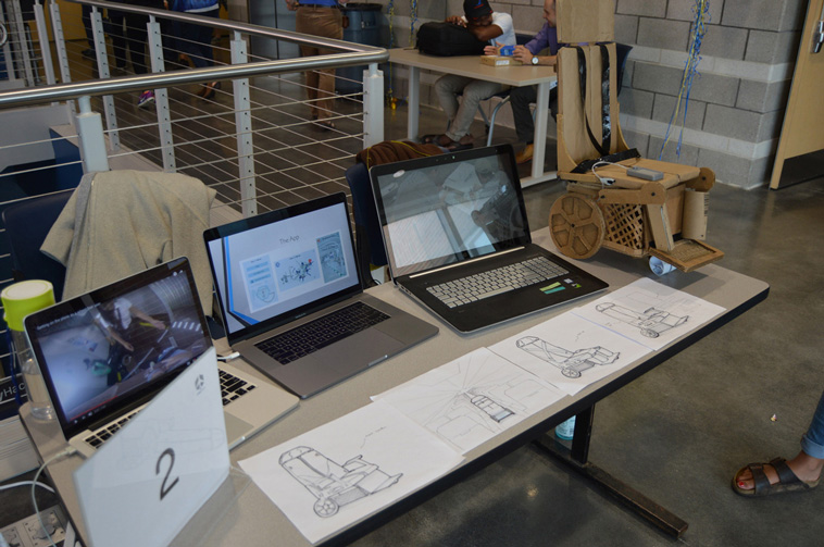 Life at CCAD, Table containing three laptops and multiple rendered images of concepts for autonomous mobility wheelchairs