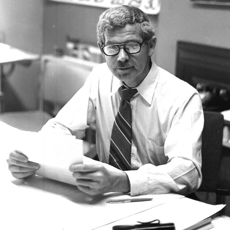 Industrial Design, Black and white photo of Bernard Stockwell sitting at table in shirt and tie holding piece of paper