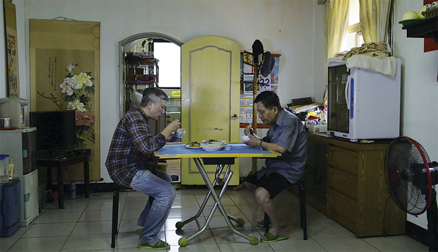 Life at CCAD, Image still from film, two people seated across from one another at a small kitchen table eating