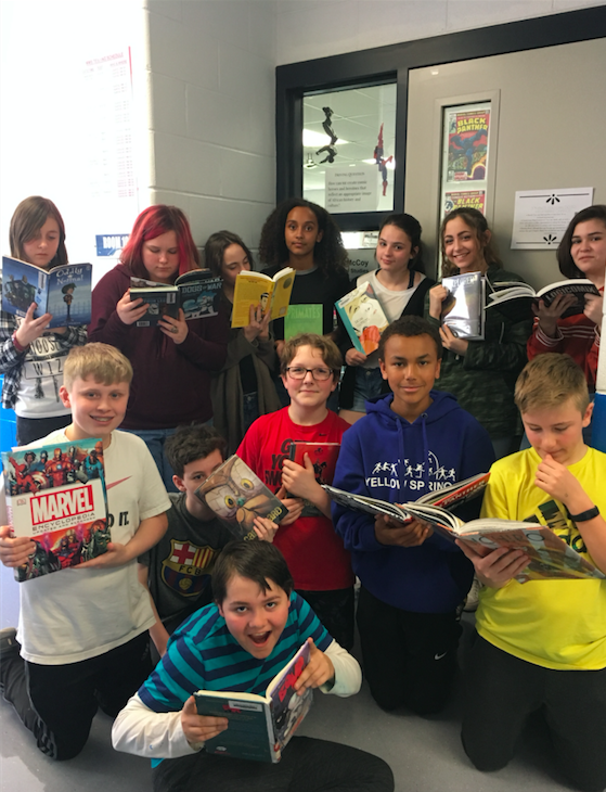 Illustration, Students pose for photo, each holding comic book