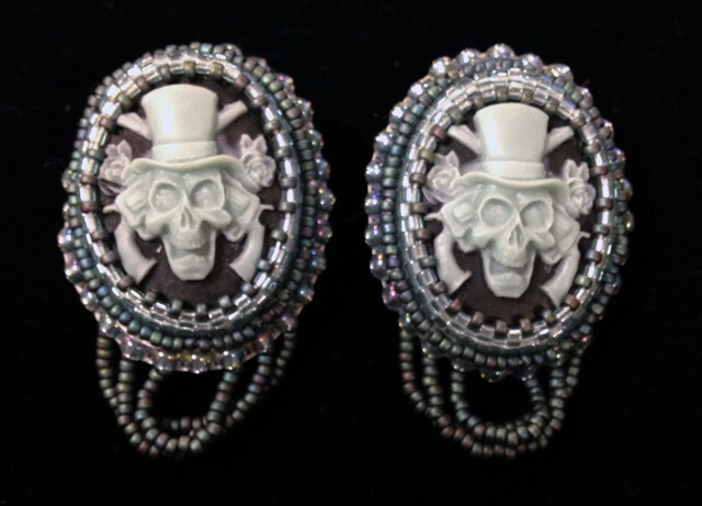 Master of Fine Arts, Image of Victorian Inspired earrings with skulls in top hats with guns and roses on a black backdrop