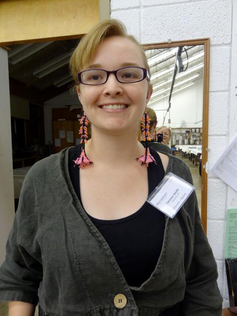 Master of Fine Arts, Headshot of Carmen Smith at Art Fair wearing a black shirt, gray jacket, and pink and black earrings