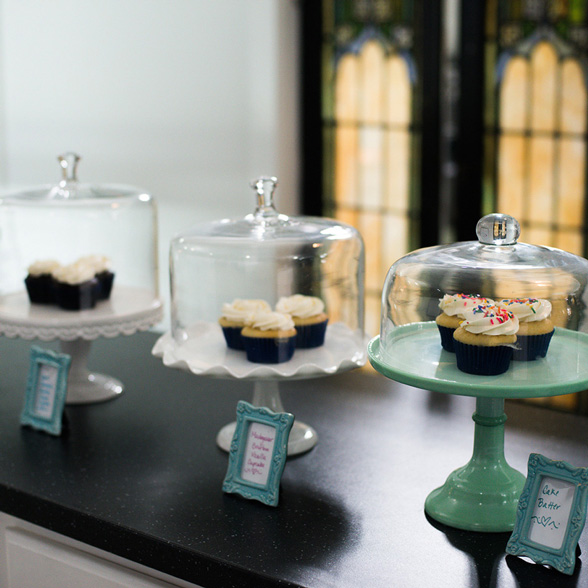 Life at CCAD, Image of cupcakes sitting in cake stands  with teal framed signs on counter at Koko Tea Salon near CCAD campus