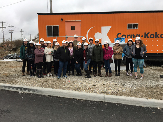 Advertising & Graphic Design, Group of students pose for photo in white hard hats in front of orange construction trailer 