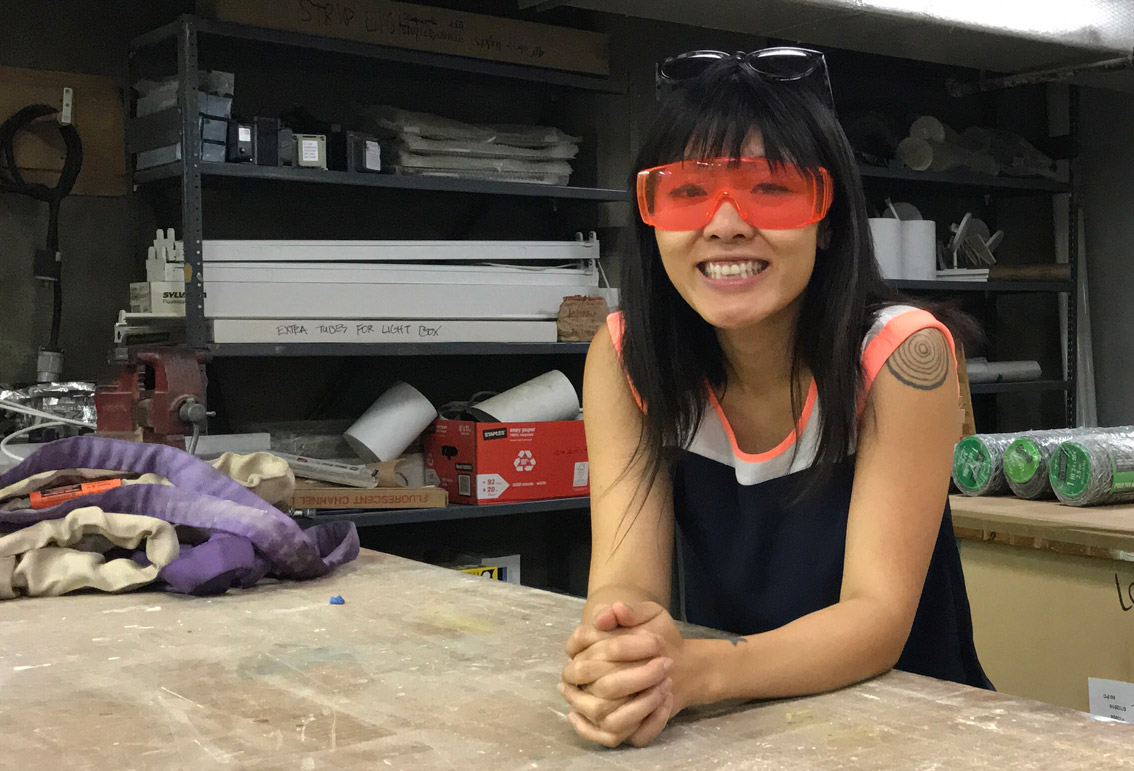 Master of Fine Arts, Linda Diec poses for photo wearing orange safety glasses