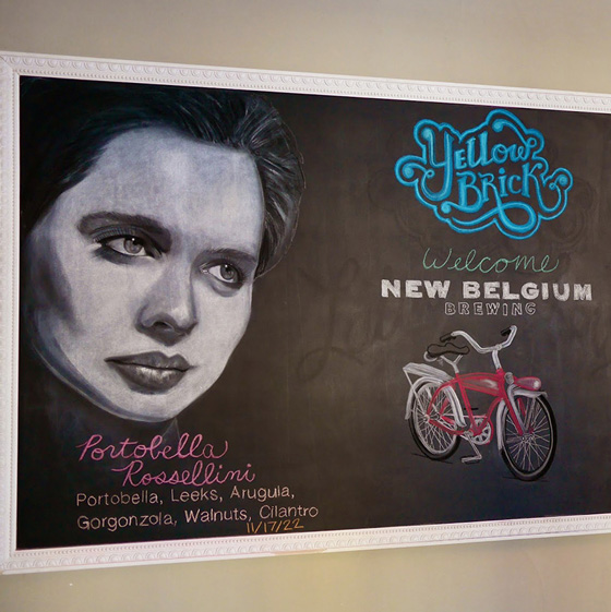 Fine Arts, Chalk Portrait of Isabella Rossellini next to Yellow Brick logo and red bicycle