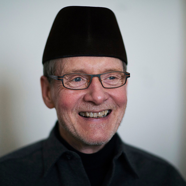 Master of Fine Arts, Headshot of Malcolm Cochran in black shirt and hat against light gray background