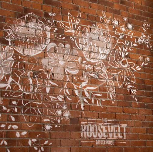 Life at CCAD, Photo of white chalk floral mural on brick wall accompanied by Roosevelt logo