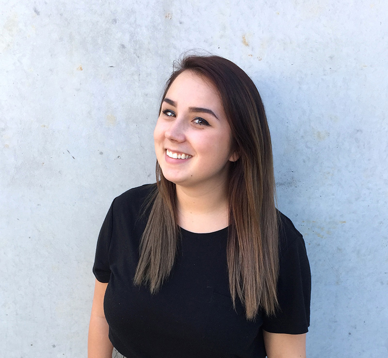 Advertising & Graphic Design, Heashot of Sarah Moore in black tshirt smiling in front of gray stone wall