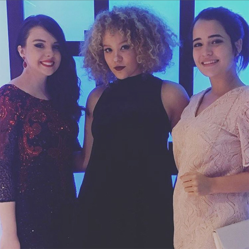 Fashion Design, Three students pose in front of blue lighted wall