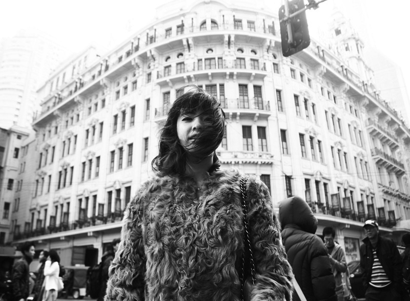 Master of Fine Arts, Black and white image of woman in fur coat on busy sidewalk in Shanghai