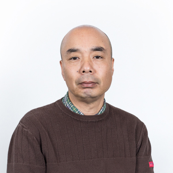 Fine Arts, Contemporary Crafts, Headshot of professor Kaname Takada in brown sweater, not smiling, against white background