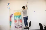 Image of student standing on chair, hanging artwork