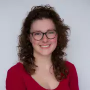 Headshot of Sam, smiling, in a red shirt