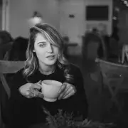 Taylor holding coffee cup seated at cafe table