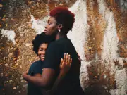 two women hugging in front of stone wall