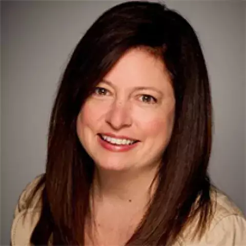 Headshot of Amy Stevenson in tan shirt, against a gradated gray background