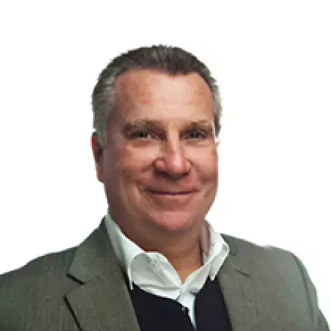 Headshot of Brian P. Kinzelman in a gray suit jacket layered over a black sweater and white collared shirt, against a white background