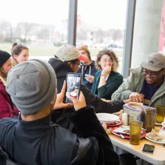 Student takes a picture of others at the dining hall.